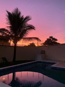 een zwembad met een palmboom en een zonsondergang bij Casa na praia in Itanhaém