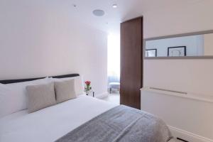 een slaapkamer met een wit bed en een spiegel bij Modern, Luxurious 1BR Flat- Heart of Covent Garden in Londen