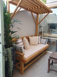 un sofá de madera sentado en un porche con almohadas en סוויטה על שביל הים en Atlit