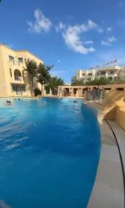 a large swimming pool with blue water at Appartement résidence Port yasmine hammamet in Hammamet