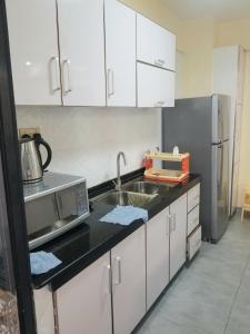 內羅畢的住宿－JVhomes2bedroom-Ndemi gardens，厨房配有白色橱柜、水槽和冰箱。