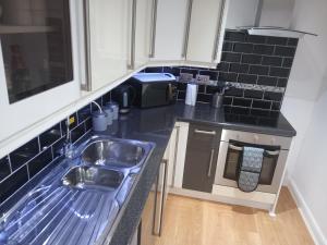 uma pequena cozinha com um lavatório e um micro-ondas em Victoria Quays Apartments, Fleetwood em Fleetwood