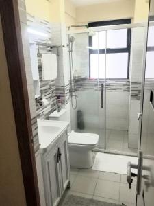 a bathroom with a toilet and a glass shower at Ndemi Garden-One and two bedrooms in Nairobi