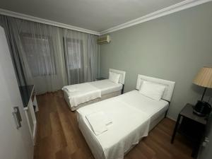Habitación con 2 camas, paredes blancas y suelo de madera. en Akkent Garden Hotel, en Fethiye