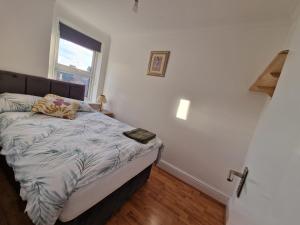 um pequeno quarto com uma cama e uma janela em CosyHomeStay Evesham Spacious home W/Free Parking & WiFi em Evesham