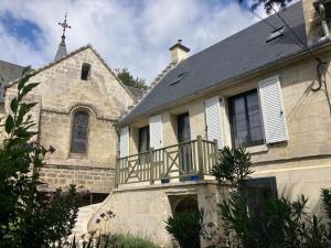 uma antiga casa de pedra com uma varanda e uma igreja em Le bois de mon coeur - studio cosy indépendant 