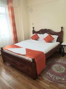 a bedroom with a bed with white sheets and orange pillows at Ndemi Garden-One and two bedrooms in Nairobi