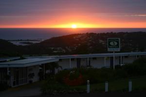 un edificio con una señal frente a una puesta de sol en Kingfisher Motel (Adults only), en Merimbula