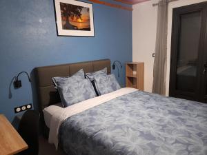 a bedroom with a bed with blue walls at LES SOMMETS DE SALAZIE CHAMBRES D'HÔTES in Salazie