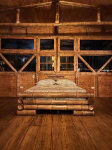 Cama en habitación con suelo y ventanas de madera en Finca Vista Hermosa, en Santa Rosa de Cabal
