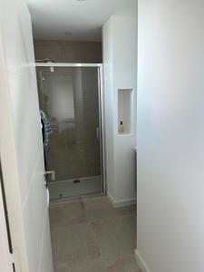 La salle de bains est pourvue d'une douche avec une porte en verre. dans l'établissement TI YANN, à Porspoder