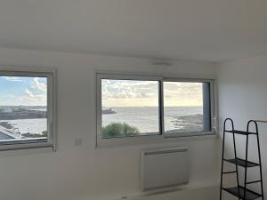 - deux fenêtres dans une chambre blanche avec vue sur l'océan dans l'établissement TI YANN, à Porspoder
