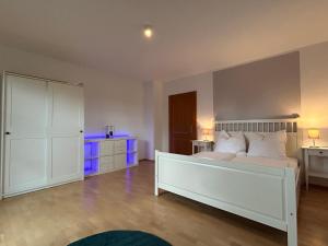 ein Schlafzimmer mit einem weißen Bett mit violetten Lichtern in der Unterkunft Gehobene Ferienwohnung Madera Campesina in Hunderdorf