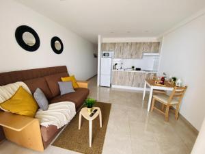 sala de estar con sofá marrón y cocina en Love in the Sea Viña del Mar by Deihu Experiences, en Adeje