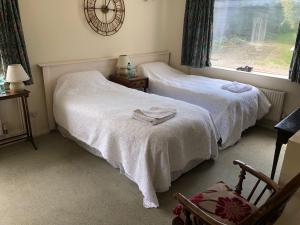 2 camas en un dormitorio con un reloj en la pared en Stable Lodge B&B, en Petham