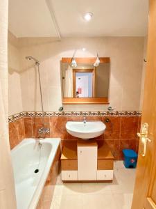 een badkamer met een wastafel, een bad en een spiegel bij Ático frontal con vistas al mar - 1ª línea Acapulco I in Oropesa del Mar