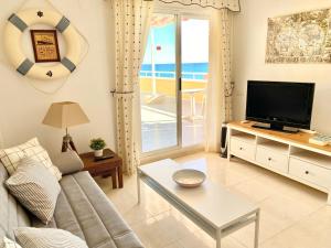 een woonkamer met een bank en een tv bij Ático frontal con vistas al mar - 1ª línea Acapulco I in Oropesa del Mar