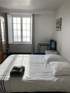 Una cama blanca en un dormitorio con una bolsa. en FACE A LA MER , L ARTISTE, en Ambleteuse