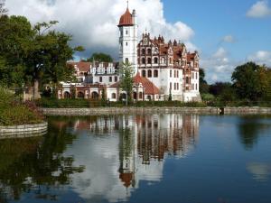 a large building with a clock tower next to a lake at Farmer Hotel Basedow in Basedow
