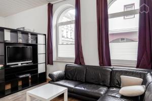 ein Wohnzimmer mit einem Ledersofa und einem TV in der Unterkunft StayINN Lindenau in Leipzig