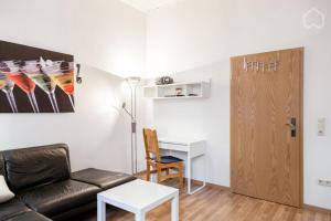 ein Wohnzimmer mit einem Sofa, einem Tisch und einem Schreibtisch in der Unterkunft StayINN Lindenau in Leipzig