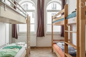 1 Schlafzimmer mit 2 Etagenbetten und 2 Fenstern in der Unterkunft StayINN Lindenau in Leipzig