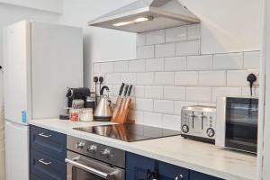 a kitchen with blue cabinets and a white tiled wall at The Derwent in Darlington