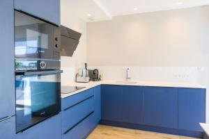 uma cozinha com armários azuis e um lavatório em Escale à Saint-Gué em Penmarcʼh