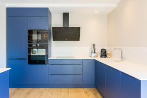 uma cozinha azul e branca com balcões e electrodomésticos brancos em Escale à Saint-Gué em Penmarcʼh