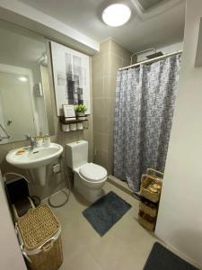 a bathroom with a toilet and a sink and a shower at The Residences at Commonwealth by Century in Manila