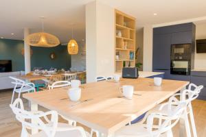 une salle à manger avec une grande table en bois et des chaises blanches dans l'établissement Escale à Saint-Gué, à Penmarcʼh