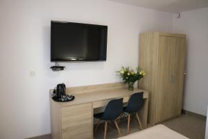 a room with a desk with two chairs and a television on the wall at Dom Gościnny Posejdon in Pobierowo