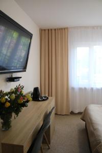 a hotel room with a television and a table with flowers on it at Dom Gościnny Posejdon in Pobierowo