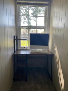 een computer op een bureau voor een raam bij Cape Cod Loft - Room near Liberty! in Lynchburg