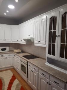 a white kitchen with white cabinets and a rug at Apartman Aleksandar, BN centar in Bijeljina