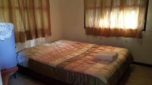 1 cama pequeña en un dormitorio con 2 ventanas en ลิ้นฟ้าแคมป์ปิ้งรีสอร์ท, en Mae Hong Son