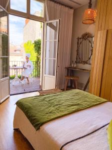 - une chambre avec un lit et une femme assise sur une terrasse couverte dans l'établissement La Course, à Bordeaux