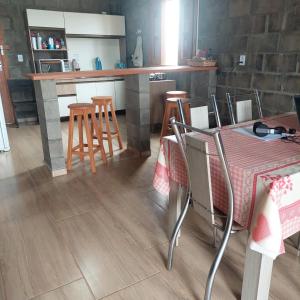 a kitchen with a table and chairs and a counter at Casa para temporada em Arroio do Silva a 900m do mar in Arroio do Silva