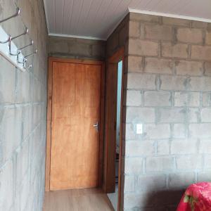 a wooden door in a room with a brick wall at Casa para temporada em Arroio do Silva a 900m do mar in Arroio do Silva