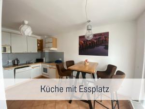 2 Zimmer App Dünengarten Lieblingsplatz Wg11 في كولونغسبورن: مطبخ مع طاولة وكراسي في غرفة
