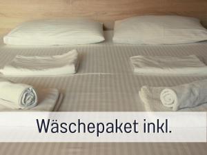 duas camas com lençóis brancos e almofadas com as palavras waseper packet inn em 2 Zimmer App Dünengarten Lieblingsplatz Wg11 em Kühlungsborn