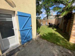 eine blaue Tür zu einem Haus mit Garten in der Unterkunft Le palmier in Saint-Georges-de-Pointindoux