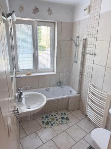 a bathroom with a tub and a sink and a window at Apartament Jurata in Jurata