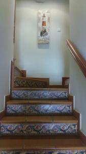 a staircase with a painting of a lighthouse on the wall at Pension Amarantos in Suances