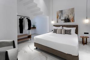 New Villa In Downtown في أثينا: غرفة نوم بيضاء مع سرير وبعض رفوف الملابس