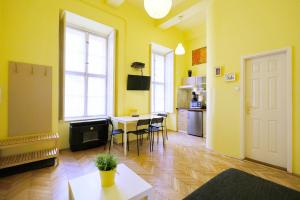 a yellow living room with a table and a kitchen at Supreme Astoria Semmelweis in Budapest