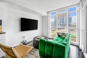 ein Wohnzimmer mit einem grünen Sofa und einem großen Fenster in der Unterkunft Family oriented Downtown Toronto 2BDRM Condo with Parking & office space in Toronto