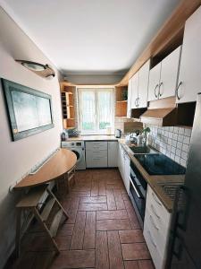 a kitchen with white cabinets and a wooden floor at Apartament Jurata in Jurata