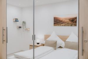 a bedroom with a bed with white sheets and pillows at Ferienwohnung am Weinberg in Bötzingen