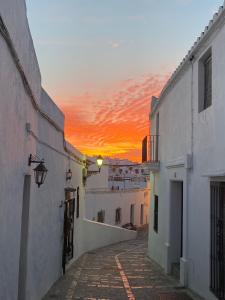 een steegje met een zonsondergang op de achtergrond bij Casa Nayib in Vejer de la Frontera